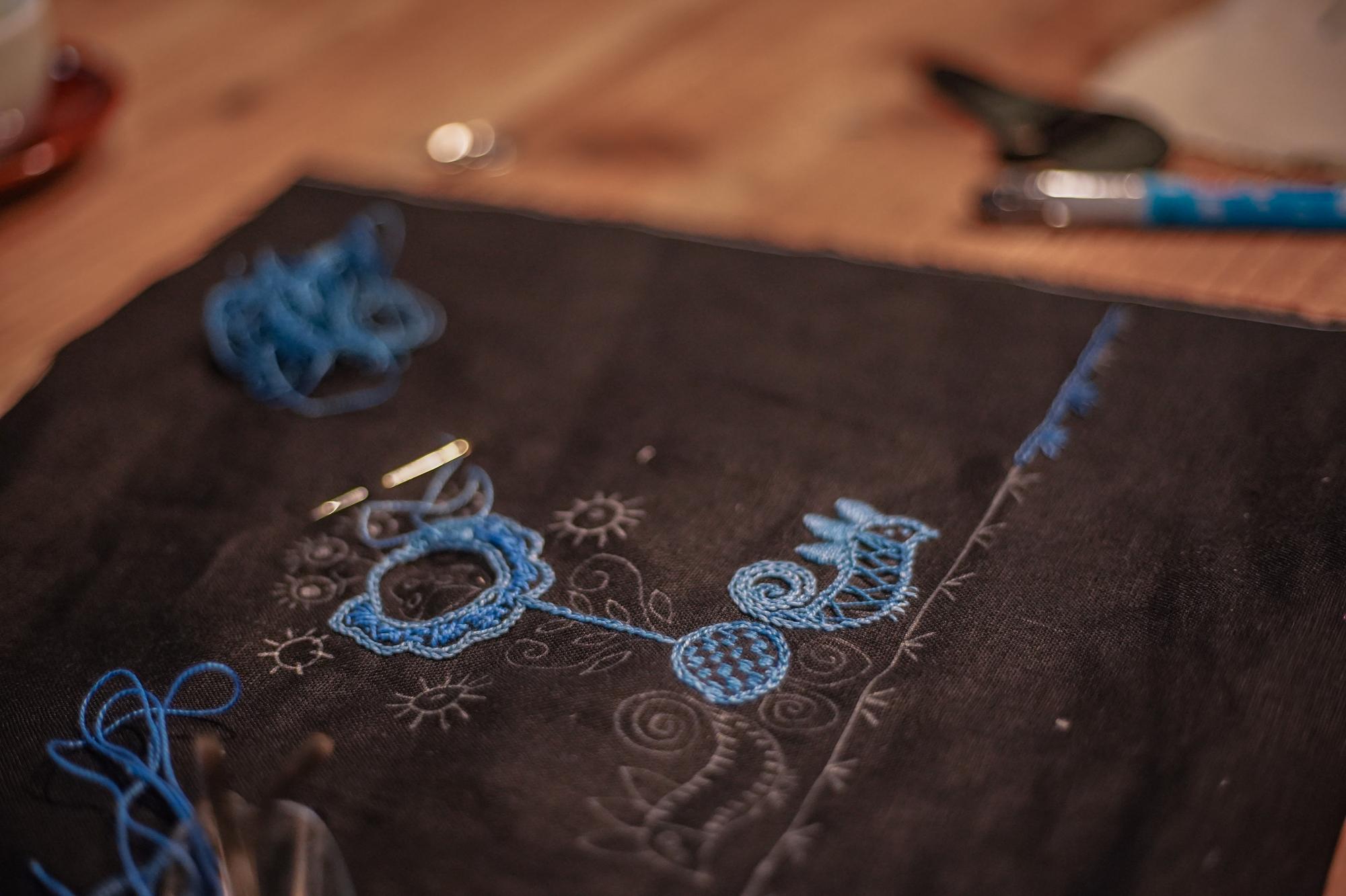 Studio table with threads, sketches and embroidered sample