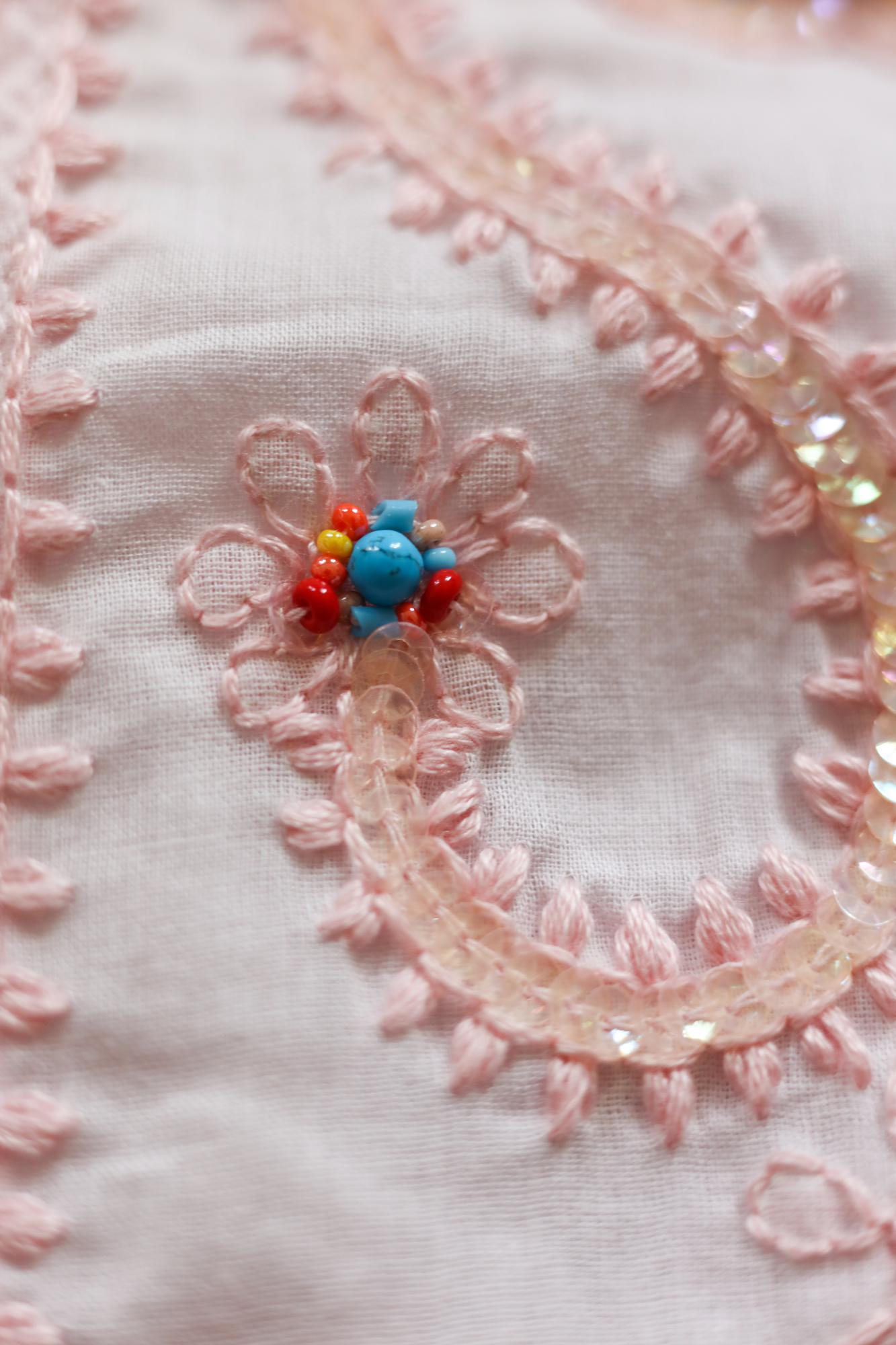Close-up of hand embroidery on linen with pastel threads